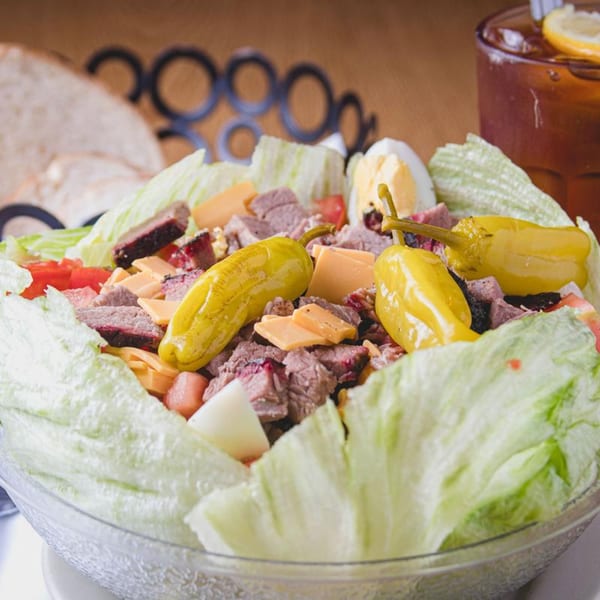 Barbecue Inn's BBQ salad with sliced meat, cheese, tomatoes, hard-boiled egg, and peppers.