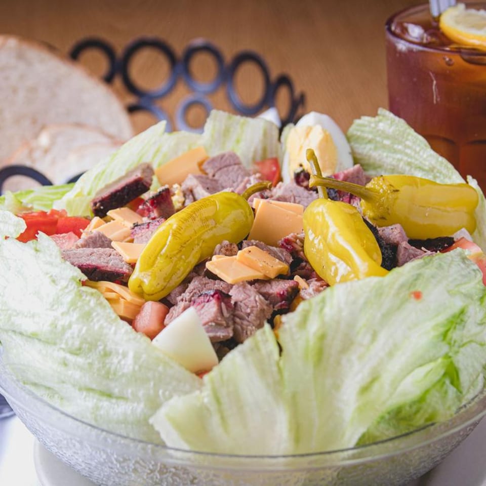 Barbecue Inn's BBQ salad with sliced meat, cheese, tomatoes, hard-boiled egg, and peppers.