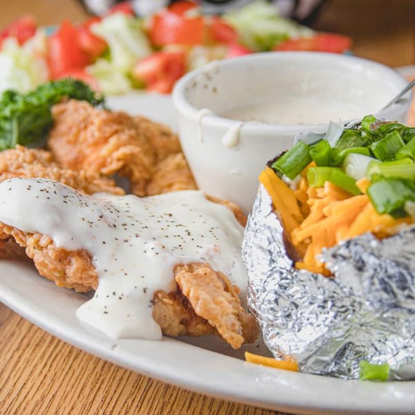 Barbecue Inn's chicken fried steak with gravy, a loaded baked potato, and a side salad.