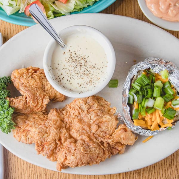 Barbecue Inn's fried chicken with gravy, a loaded baked potato, and a side salad.